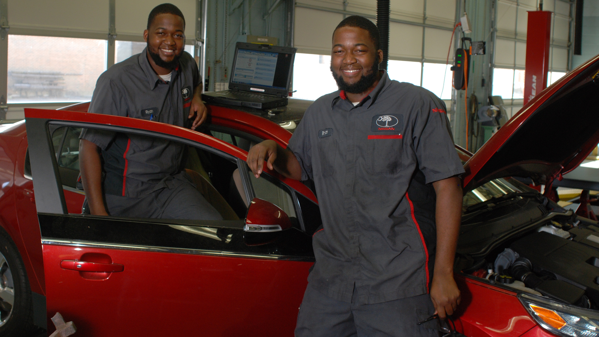 two auto tech students smiling in garage