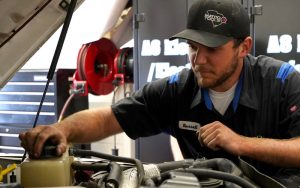 Auto student under hood of a car