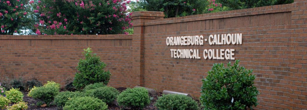 photo of brick gate with college name on it.